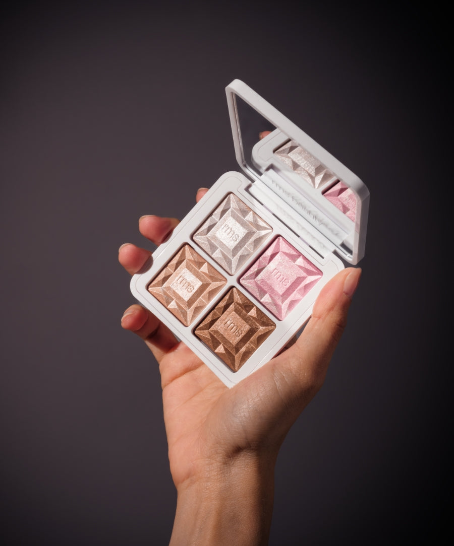 Hand holding an open ReDimension Daily Glow Palette showing four shimmery shades in neutral tones and pink, with a mirror inside the white compact case.