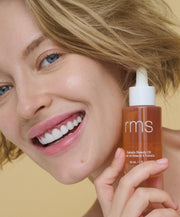 Model holding RMS Kakadu Beauty Oil in a clear bottle with a dropper