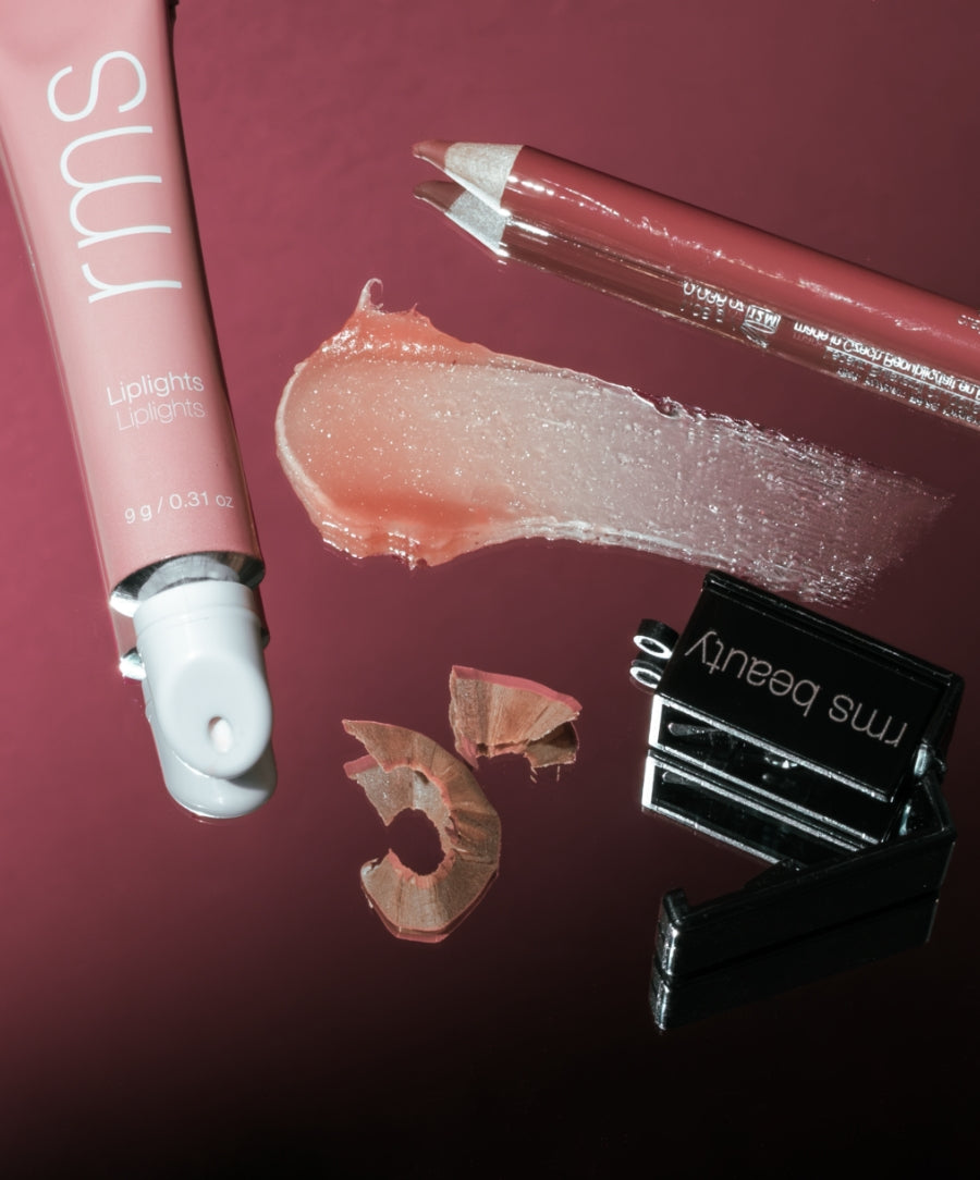 The Line & Shine Kit featuring a rosy lip pencil highlighting balm tube creamy swatch and black sharpener on a burgundy surface